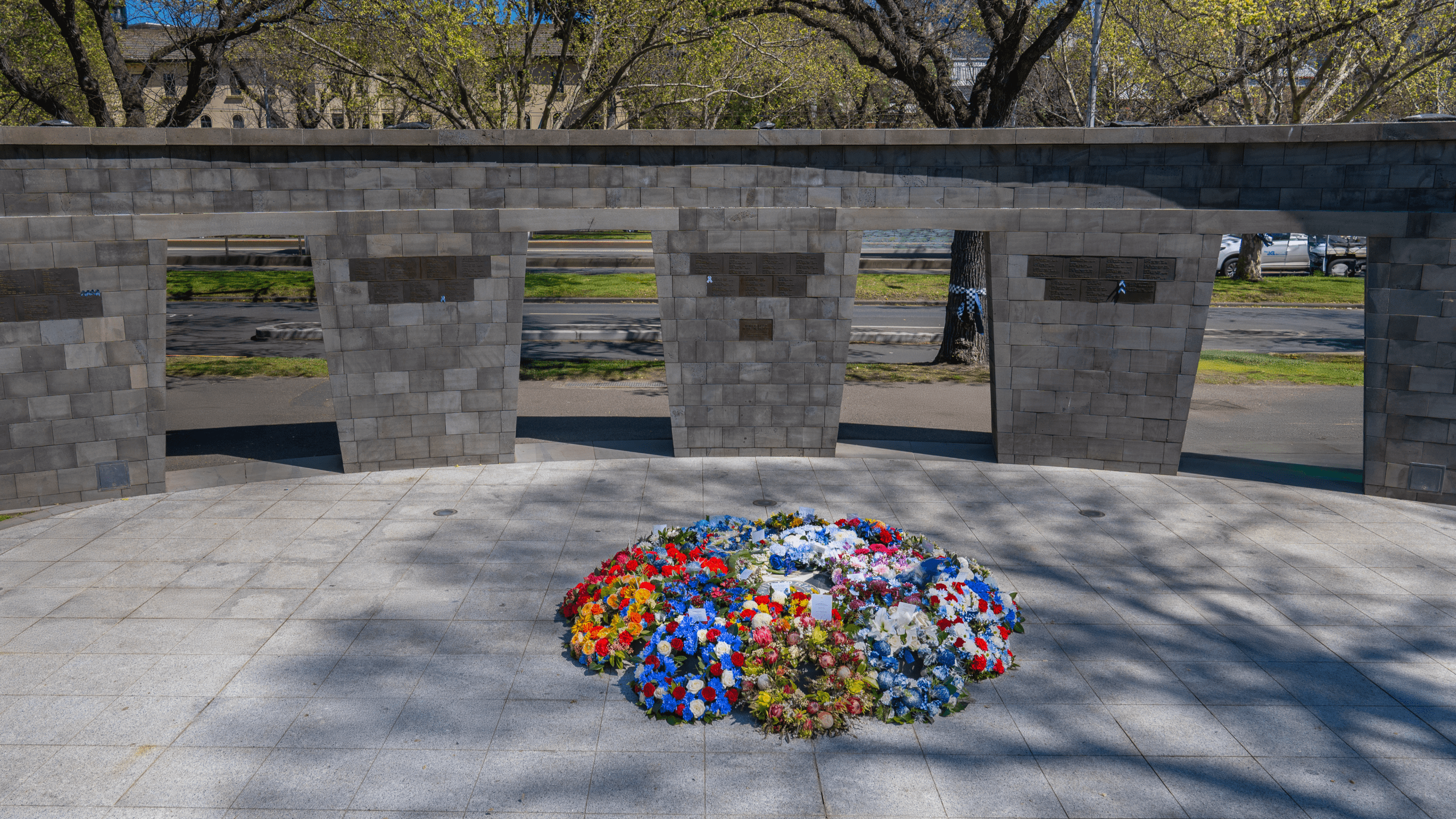 The Honour Wall at the Police Memorial, with flower wreaths laid in a circle. 